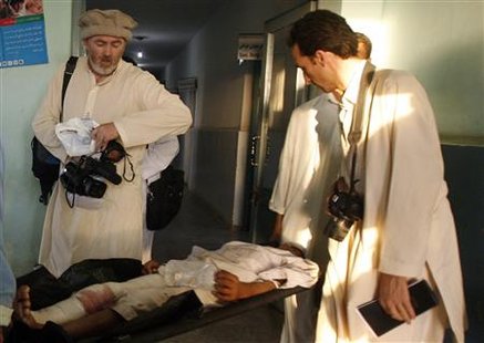 




British reporter for the New York Times Stephen Farrell (L) and Afghan reporter Mohammad Sultan Munadi (R) film and talk to a wounded Afghan man in a hospital in Kunduz in this September 4, 2009 photo. REUTERS/Omar Sobhani

