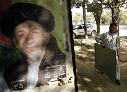 An Afghan man carries a sheet of iron next to a poster of President Hamid Karzai at his shop in Kabul September 12, 2009. REUTERS/Omar Sobhani
An Afghan man carries a sheet of iron next to a poster of President Hamid Karzai at his shop in Kabul September 12, 2009. REUTERS/Omar Sobhani