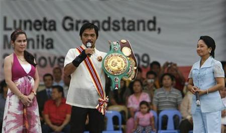 
Philippine President Gloria Macapagal Arroyo (R) looks at world boxing champion Manny Pacquiao as he shows the crowd his championship belt, in Luneta park in Manila November 20, 2009. REUTERS/Romeo Ranoco
