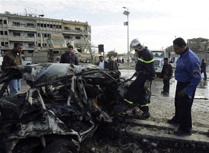 
A policeman and a civil defence personnel officer inspect a burnt vehicle at the site of a bomb attack in central Baghdad January 26, 2010. REUTERS/Saad Shalash
