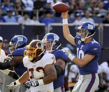 
New York Giants quarterback Eli Manning (R) lofts a short complete pass over the head of Washington Redskins defensive tackle Lorenzo Alexander in the first quarter of their NFL football game in East Rutherford, New Jersey, September 13, 2009 file photo. REUTERS/Ray Stubblebine
