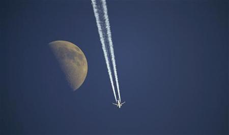 
An aircraft flies past the moon over Anterselva, northwest Italy, January 23, 2010. REUTERS/Alessandro Bianchi
