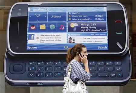 
A woman uses her mobile telephone as she passes a Nokia advert in London July 20, 2009. REUTERS/Luke MacGregor
