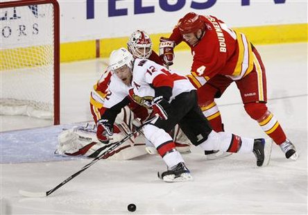 
Calgary Flames defencemen Jay Bouwmeester (R) tries to keep Ottawa Senators forward Mike Fisher (L) from getting the puck in front of goalie Miikka Kiprusoff during the third period of their NHL game in Calgary, March 11, 2010. REUTERS/Todd Korol
