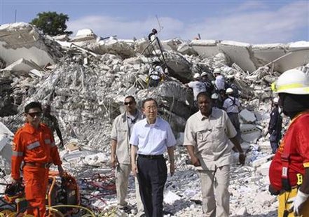 
U.N. Secretary-General Ban Ki-moon inspects the site of the former headquarters of the United Nations Stabilization Mission in Haiti (MINUSTAH) in Port-au-Prince, as rescue workers work to free a man in the background, January 17, 2010. REUTERS/Louis Charbonneau
