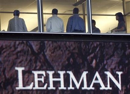 
People stand next to windows above an exterior sign at the Lehman Brothers headquarters in New York in this September 16, 2008 file photo. REUTERS/Chip East/Files
