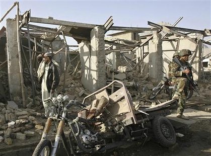 
An Afghan National Army (ANA) soldier (R) keeps watch as a passer-by views the site of a blast near Kandahar prison March 14, 2010. REUTERS/Ahmad Nadeem
