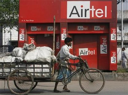 
A man pulls a cycle-rickshaw with goods in front of a shop with boards of Bharti Airtel in Kolkata February 18, 2010. REUTERS/Parth Sanyal
