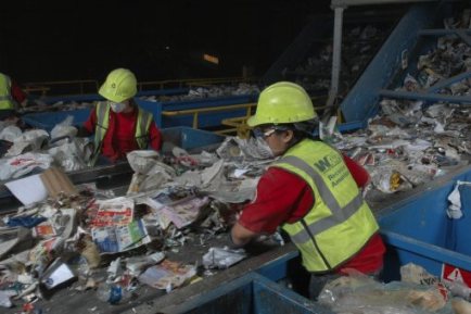 Workers help separate comingled recyclables at a single-stream recycling facility. Workers help separate comingled recyclables at a single-stream recycling facility.