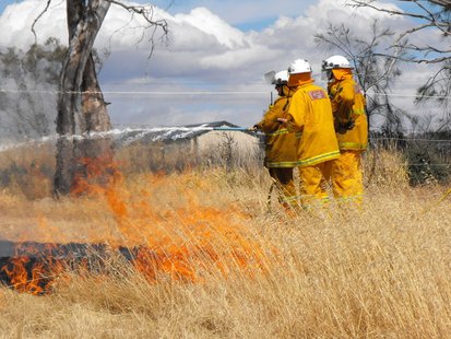 Firefighters put water on a small grass fire.