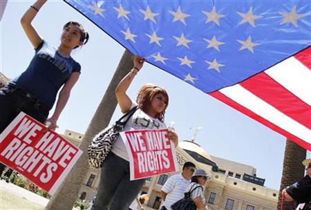
People hold the U.S. flag as they protest against Senate Bill 1070 outside the Arizona State Capitol in Phoenix, Arizona April 25, 2010. REUTERS/Joshua Lott
