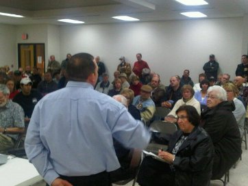 Rob Hughes of Rothschild listens as residents speak out against a proposed $250 million woody biomass power plant in the village.