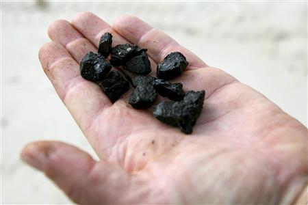 
Todd Farrar with SCAT (Shoreline Cleanup Assessment Team) holds up hard tar balls found on the beach in Pass Christian, Mississippi May 12, 2010. REUTERS/Sean Gardner
