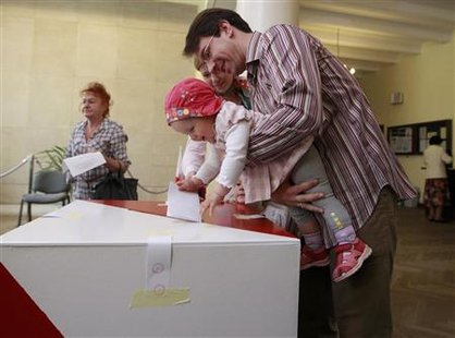 A man holds a child, while casting his vote at a polling station in Warsaw during presidential elections June 20, 2010. REUTERS/Peter Andrews
A man holds a child, while casting his vote at a polling station in Warsaw during presidential elections June 20, 2010. REUTERS/Peter Andrews
