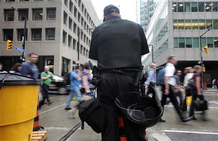 
A police officer stands guard as people cross the street ahead of the G20 summit in Toronto, June 22, 2010. REUTERS/Mark Blinch
