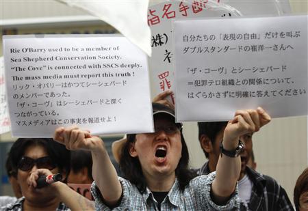 
An activist protesting against the screening of the movie "The Cove" holds placards in front of a theatre in Tokyo July 3, 2010. Protesters gathered at the Japanese opening of "The Cove", a controversial Oscar-winning documentary about a grisly annual dolphin hunt. Dozens of polices and some 50 people, both for and against the screening, faced off in front of a theatre in Tokyo's Shibuya district on Saturday. REUTERS/Issei Ka