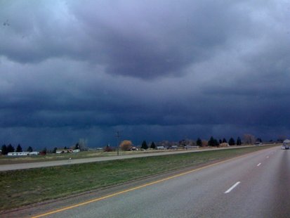 Storm clouds gather along a rural stretch of highway.