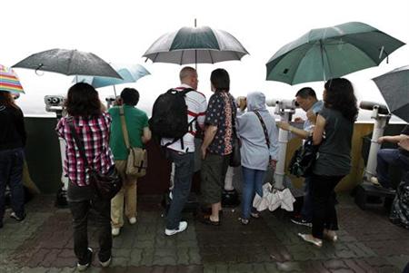 
Tourists look north through pairs of binoculars in the rain at the Dora observation post near the demilitarised zone separating the two Koreas in Paju, about 55 km (34 miles) north of Seoul, August 25, 2010. Former U.S. President Jimmy Carter has left the United States and is en route to North Korea on a mission to win the release of Aijalon Mahli Gomes, an American being held prisoner there, South Korea's Yonhap news agency said on Wednesday. R