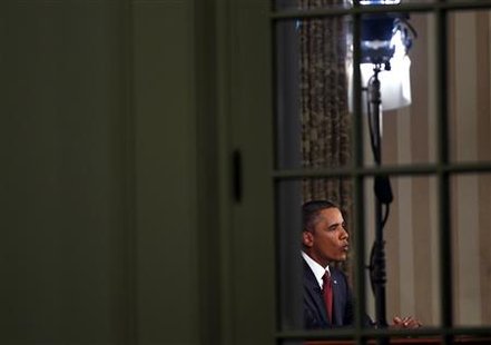 
U.S. President Barack Obama is seen in the Oval Office through a window as he addresses the nation about the end of the U.S. combat mission in Iraq at the White House in Washington, August 31, 2010. REUTERS/Jim Young
