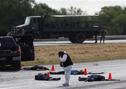 
A forensic worker takes pictures at a crime scene where five hitmen were killed in a shootout with soldiers in the municipality of Juarez, neighbouring Monterrey September 3, 2010. REUTERS/Tomas Bravo
