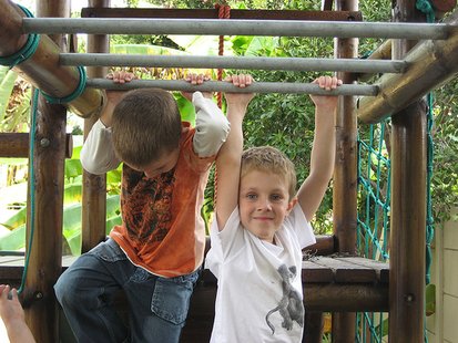 Two children play on a set of monkey bars