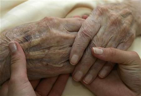 
A young carer holds the hands of an elderly woman in a residential home for the elderly in Planegg near Munich June 19, 2007. REUTERS/Michaela Rehle
