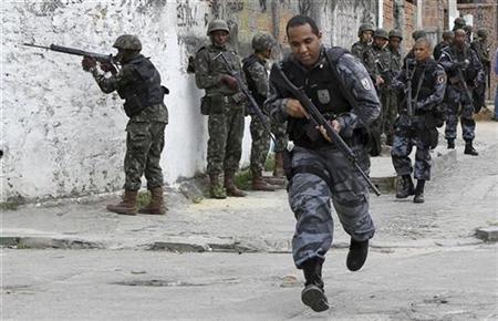 
A police officer runs during an operation at Nova Brasilia slum in Rio de Janeiro November 26, 2010. REUTERS/Sergio Moraes
