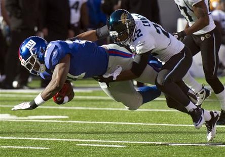 
New York Giants running back Brandon Jacobs gets a first down as he is tackled by Jacksonville Jaguars cornerback Don Carey (22) in the first quarter of their NFL game in East Rutherford, New Jersey, November 28, 2010. REUTERS/Ray Stubblebine
