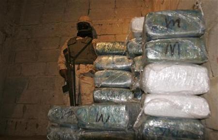 
A Mexican soldier stands next to packages containing marijuana inside a tunnel found under the Mexico-U.S. border in Tijuana November 26, 2010. REUTERS/Jorge Duenes
