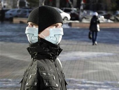 
A man wearing a mask is reflected in the mirror window as he leaves a shop in the centre of the Siberian city of Krasnoyarsk, November 3, 2009. REUTERS/Ilya Naymushin
