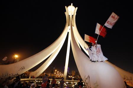 
Protesters wave Bahraini national flags after they climb up onto the Pearl Roundabout as they celebrate in Pearl Square in the capital Manama February 19, 2011. REUTERS/Hamad I Mohammed.
