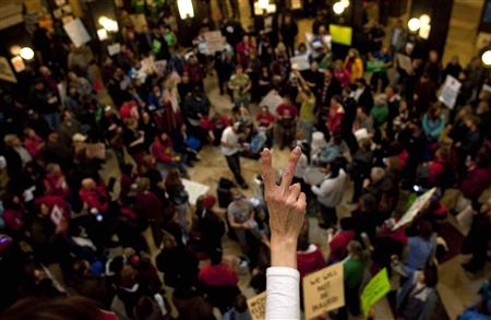 A protestor gestures at the Capitol building, after a week's mass protest against a proposed bill by Republican Governor Scott Walker, in Madison, Wisconsin February 21, 2011. Wisconsin Governor Walker, whose bid to reduce public employee union bargaining power has triggered public protests, said on Sunday he expected Democrats who oppose his plan to return to the state and debate the issue this week. REUTERS/Darren Hauck
A protestor gestures at the Capitol building, after a week's mass protest against a proposed bill by Republican Governor Scott Walker, in Madison, Wisconsin February 21, 2011. Wisconsin Governor Walker, whose bid to reduce public employee union bargaining power has triggered public protests, said on Sunday he expected Democrats who oppose his plan to return to the state and debate the issue this week. REUTERS/Darren Hauck