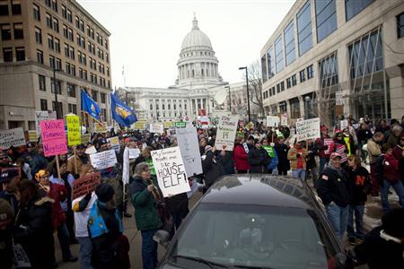 Demonstrators march around the State Capitol building as they protest against the proposed budget cuts from Wisconsin Governor Scott Walker, in Madison February 25, 2011. Credit: REUTERS/Darren Hauck Demonstrators march around the State Capitol building as they protest against the proposed budget cuts from Wisconsin Governor Scott Walker, in Madison February 25, 2011. Credit: REUTERS/Darren Hauck