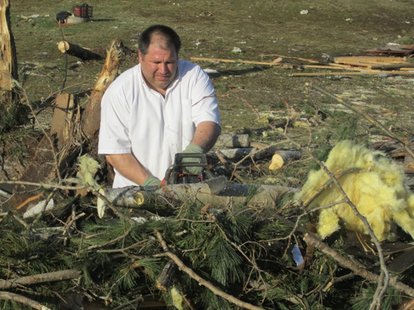 A man cuts through trees that split in half during a tornado on Merrill's north side on April 10, 2011