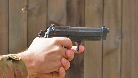 A handgun being fired at a firing range. A handgun being fired at a firing range.