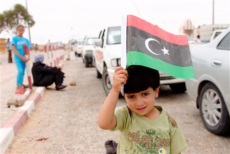 
A Libyan boy holds up a Kingdom of Libya flag at a checkpoint after crossing from Libya into Tunisia at the border crossing in Dehiba May 7, 2011. REUTERS/Anis Mili
