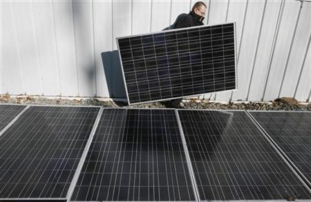 
Engineer homeowner Mike Strizki carries a solar panel past an array of panels at the shop next to his residence in Hopewell, New Jersey, January 4, 2007. REUTERS/Tim Shaffer
