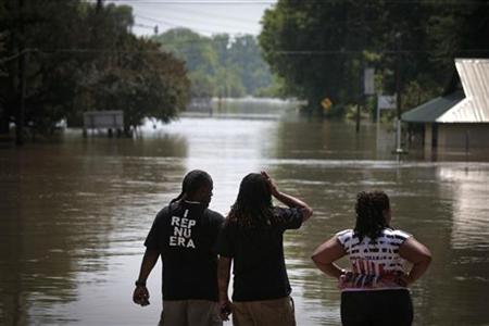 
People look over water from the bulging Mississippi River that flooded homes and businesses in St. Francisville, Louisiana May 21, 2011. REUTERS/Lee Celano
