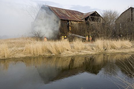Firefighters are seen putting out a fire in a nearby barn stock image. Firefighters are seen putting out a fire in a nearby barn stock image.