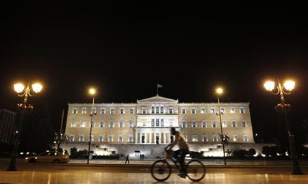 A man rides his bicycle past the parliament building in Athens A man rides his bicycle past the parliament building in Athens