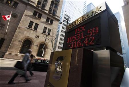 People walk by a sign displaying TSX information in Toronto People walk by a sign displaying TSX information in Toronto