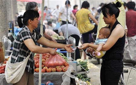A woman holding her child buys tomatoes at a market in Heze city A woman holding her child buys tomatoes at a market in Heze city