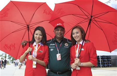 Lotus Formula One team principal Tony Fernandes poses with Air Asia flight attendants before the Malaysian F1 Grand Prix at Sepang circuit