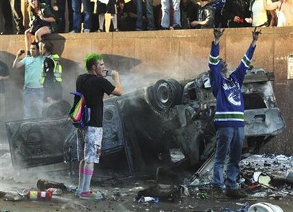 Canucks fans scream and take photos of an overturned burnt pickup truck during riots in downtown Vancouver after the Canucks lost the NHL St Canucks fans scream and take photos of an overturned burnt pickup truck during riots in downtown Vancouver after the Canucks lost the NHL St