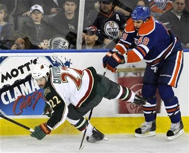 Edmonton Oilers' Peckham hits Minnesota Wild's Clutterbuck to the ice during their NHL hockey game in Edmonton