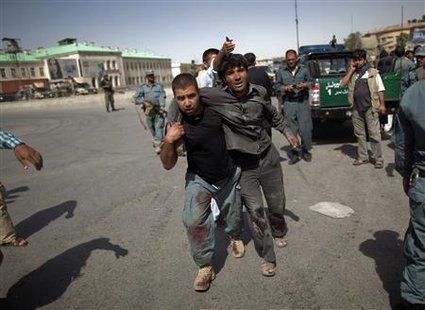 Afghan policeman helps a wounded man away from the site of an attack at a Kabul police station Afghan policeman helps a wounded man away from the site of an attack at a Kabul police station