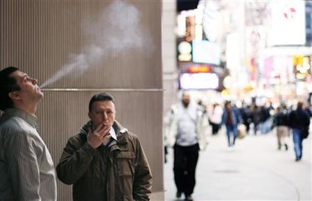 A pair of smokers stand outside of an office building in the Times Square region of New York A pair of smokers stand outside of an office building in the Times Square region of New York