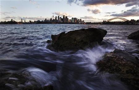 Small waves crash over rocks across the harbour from the Sydney city skyline Small waves crash over rocks across the harbour from the Sydney city skyline