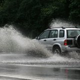An SUV runs through a flooded road