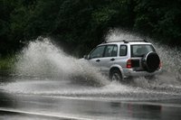 An SUV runs through a flooded road